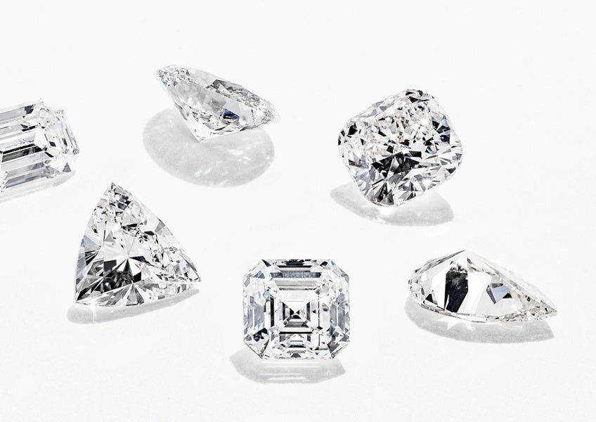 A varied selection of unique MiaDonna Lab-Grown Diamonds scattered on a white surface. 
