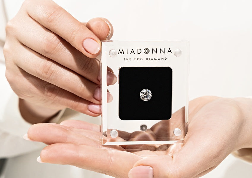 Hands holding a round cut, sustainable MiaDonna Lab-Grown Diamond in a special case